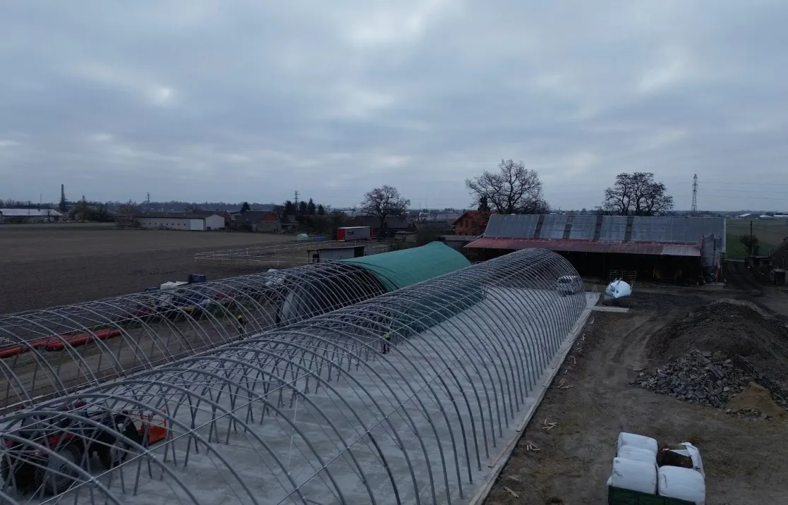 Steel arch frames being erected on a farm, aerial view